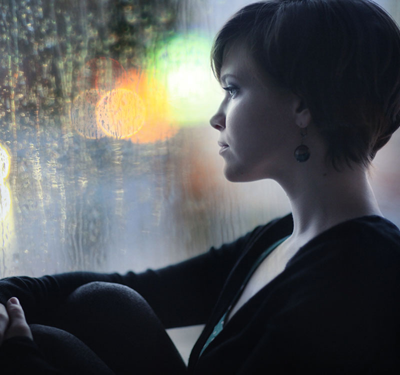 sad girl on the windowsill looking out the window sad girl on the windowsill looking out the window